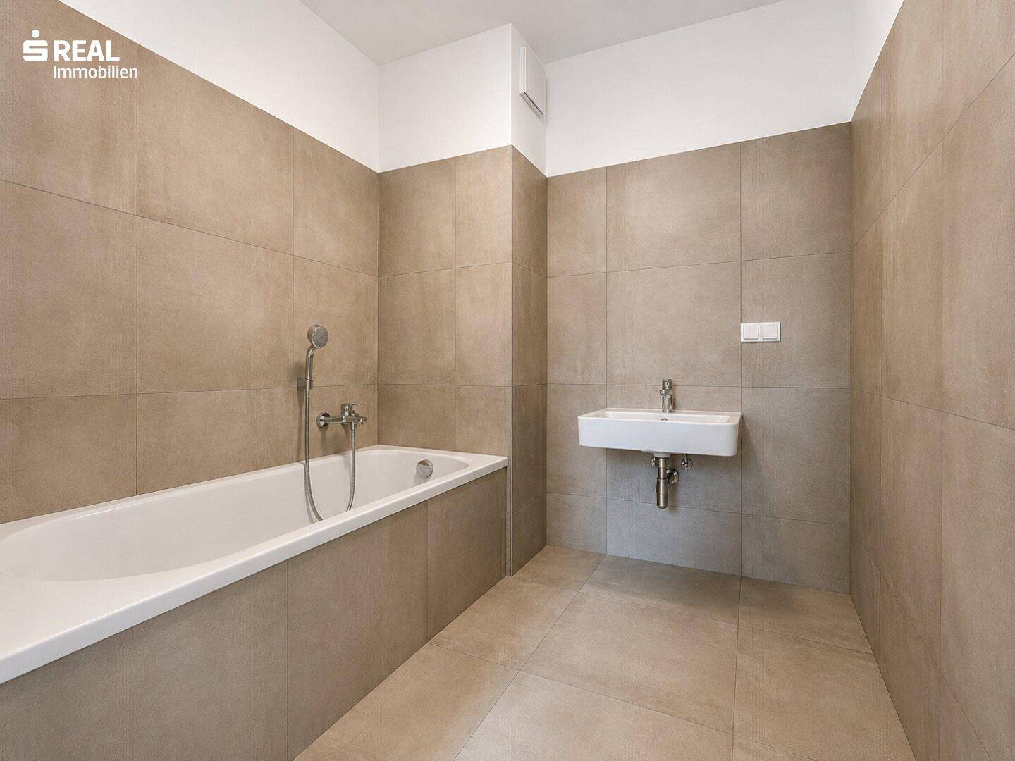 Modernes Badezimmer mit beigefarbenen Fliesen, integrierter Badewanne und wandmontiertem Waschbecken.