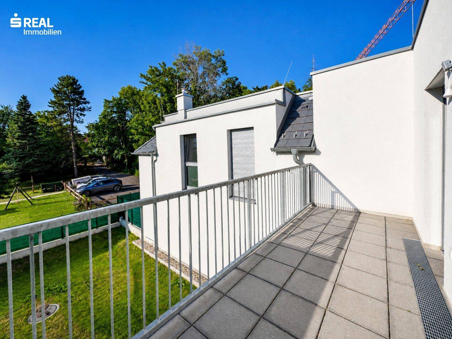 Großer Balkon mit Fliesenboden und Metallgeländer, bietet einen weiten Blick ins Grüne.