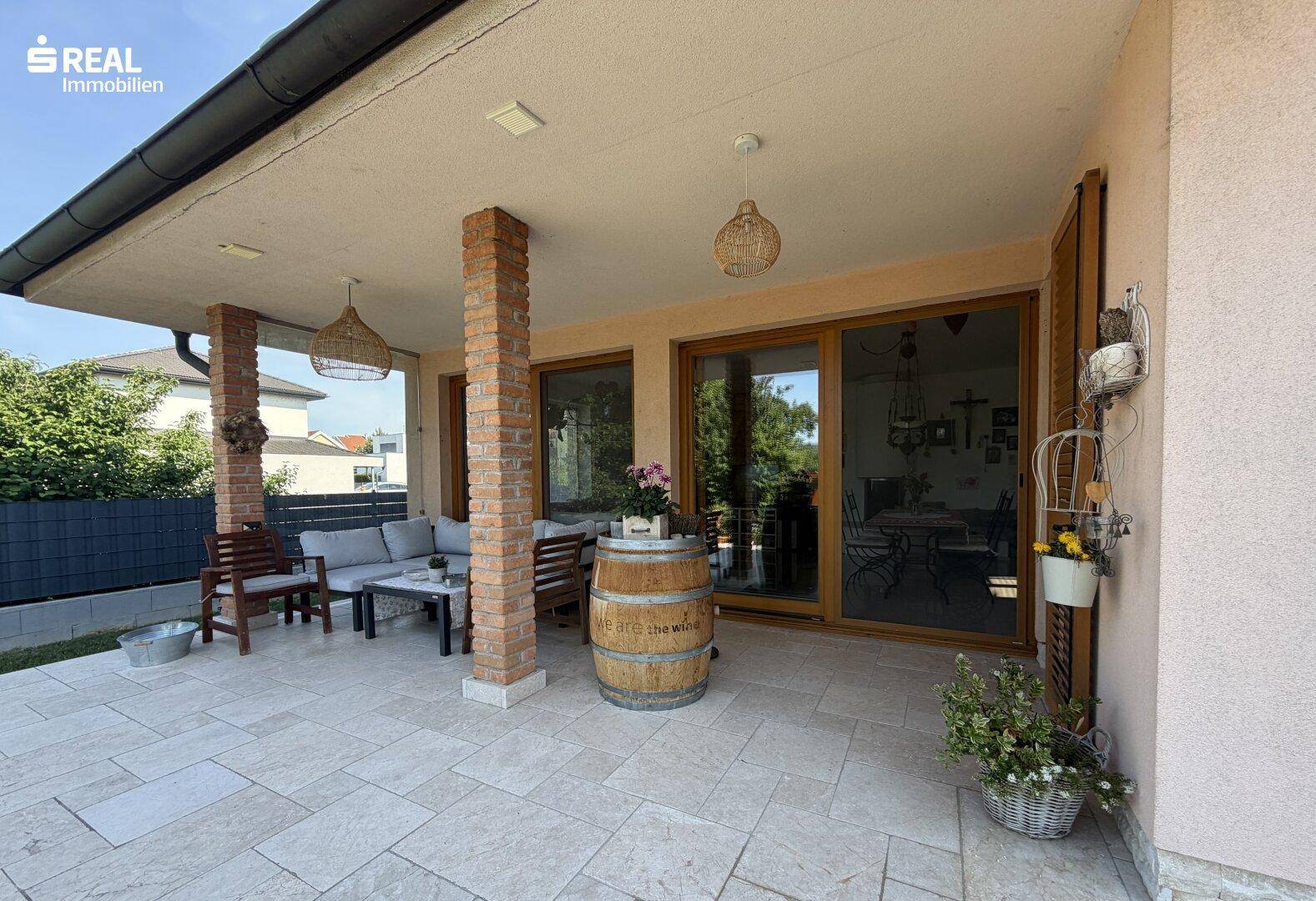 Überdachte Terrasse mit bequemen Sitzgelegenheiten und Fliesenboden, ideal für entspannte Stunden im Freien.