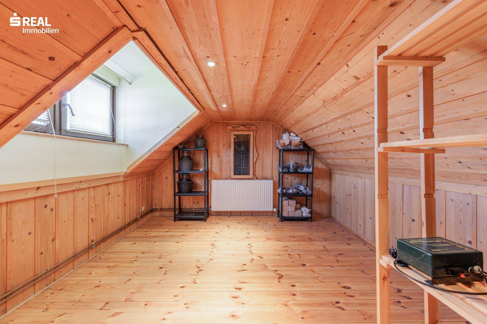 Praktischer Abstellraum im Dachgeschoss mit Holzverkleidung, Holzboden und Dachfenster.