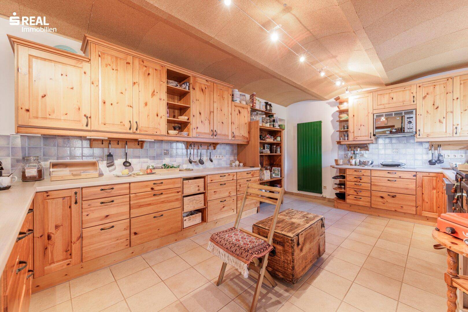 Geräumige Küche im Landhausstil mit vielen Holzschränken, Fliesenboden und traditioneller Ausstattung.
