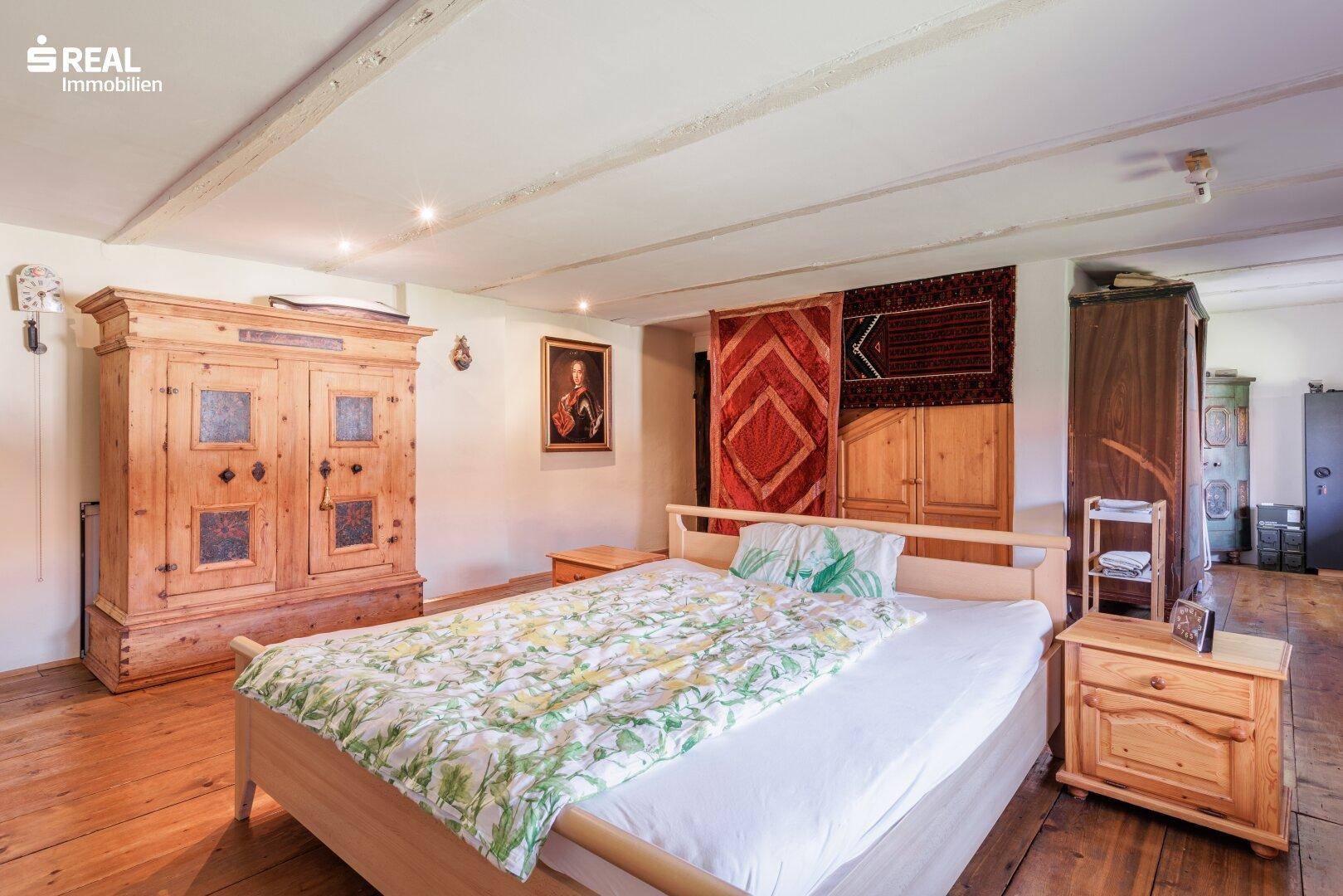 Schlafzimmer mit Holzdielenboden, Doppelbett und großen Holzschränken im traditionellen Stil.