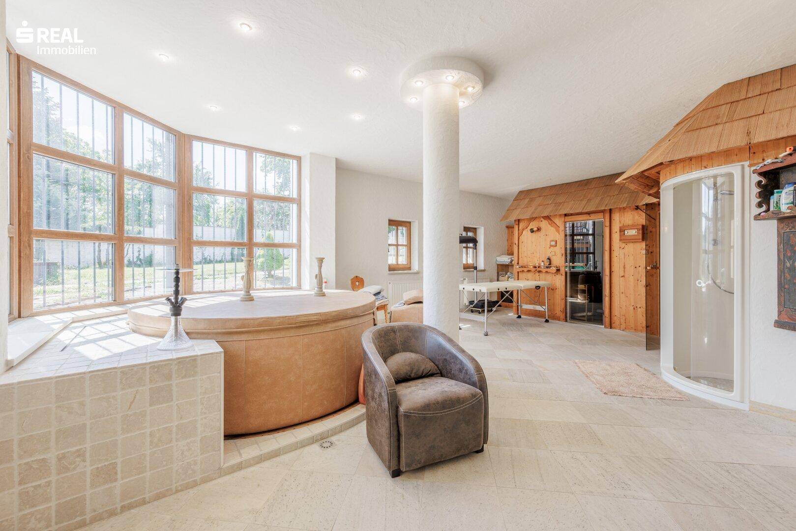Luxuriöser Wellnessbereich mit großem Whirlpool, Sauna, Duschkabine und großen Fenstern.
