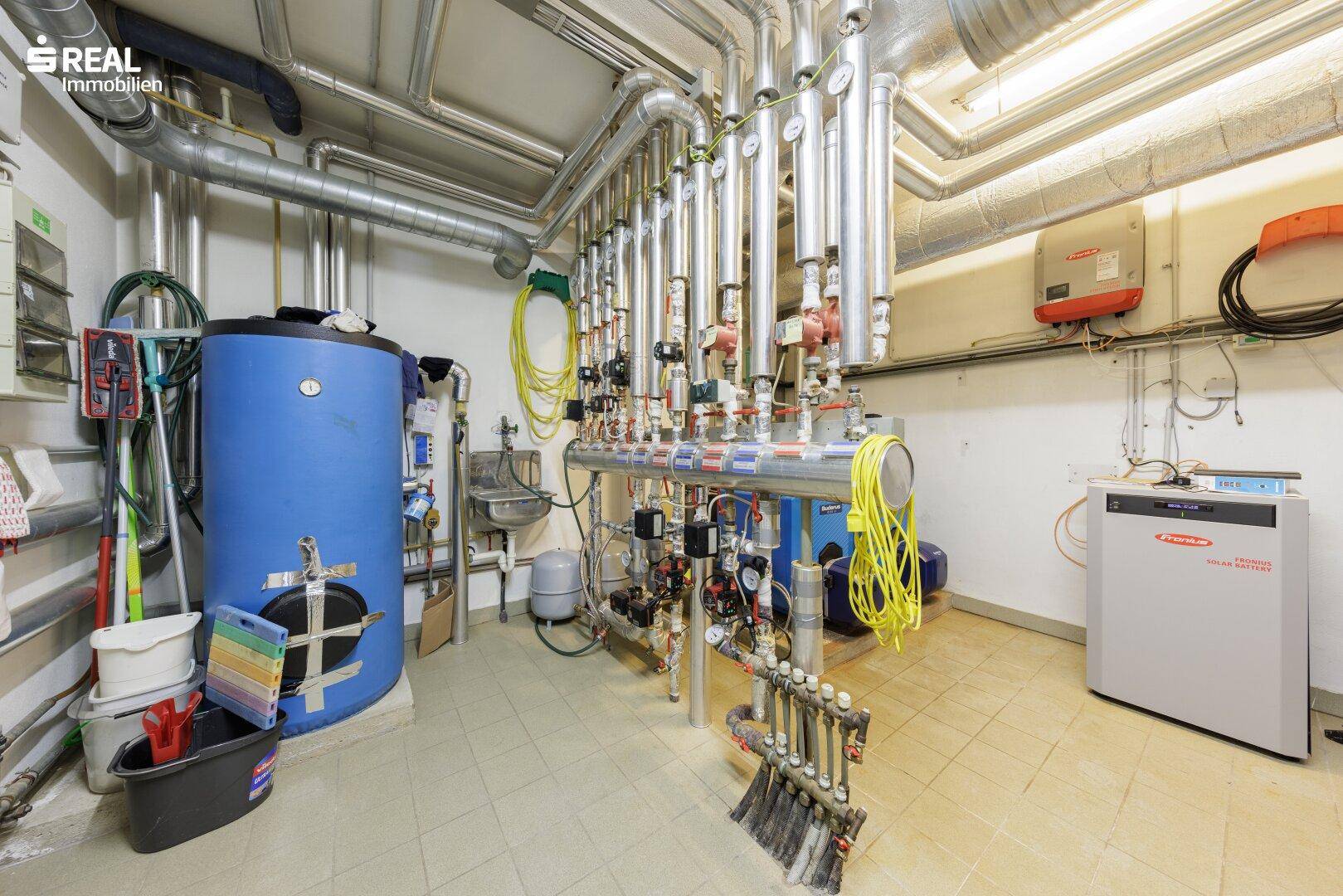Technikraum mit großem Warmwasserspeicher, komplexer Verrohrung und moderner Heizungsanlage.
