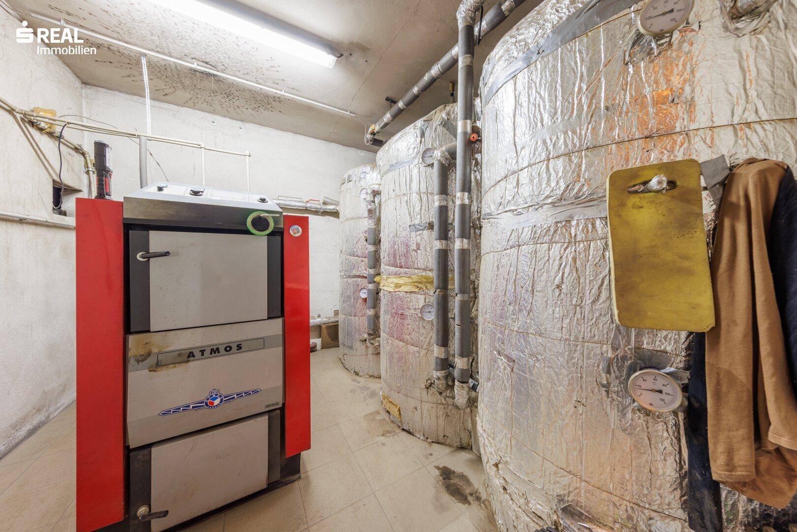 Heizungsraum mit großem Holzvergaserofen und mehreren isolierten Pufferspeichern.