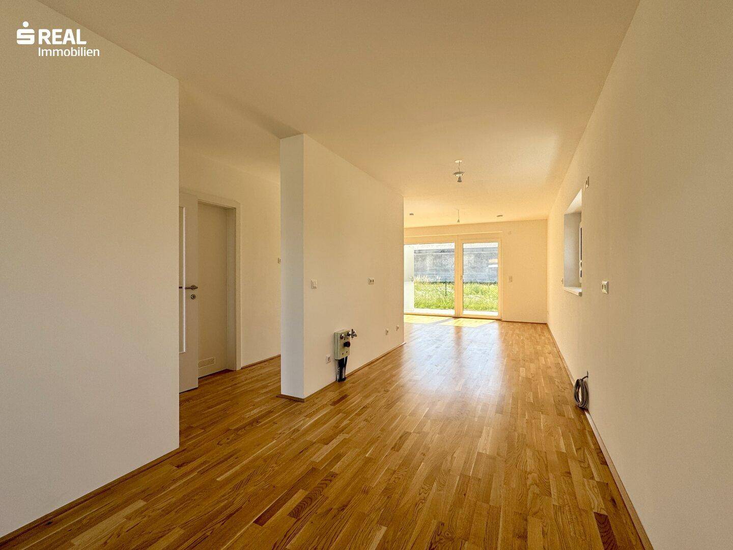 Offener Wohnbereich mit warmem Parkettboden und viel Tageslicht, bereit zur individuellen Gestaltung.