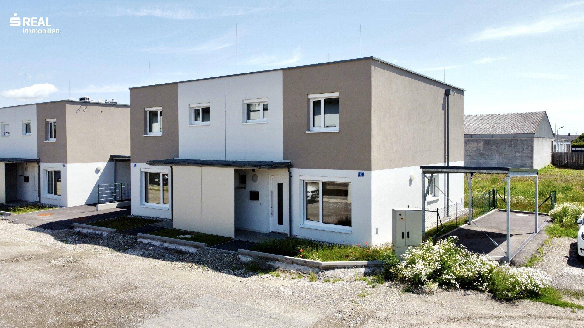 Ansicht der modernen Reihenhäuser mit schlichter Fassade und Carport-Struktur.