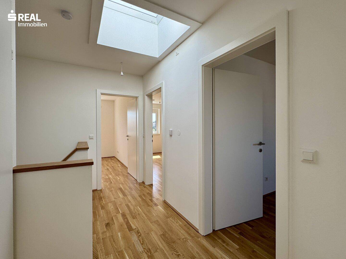 Heller Flur im Obergeschoss mit Holzboden und Dachfenster, sorgt für viel Licht.