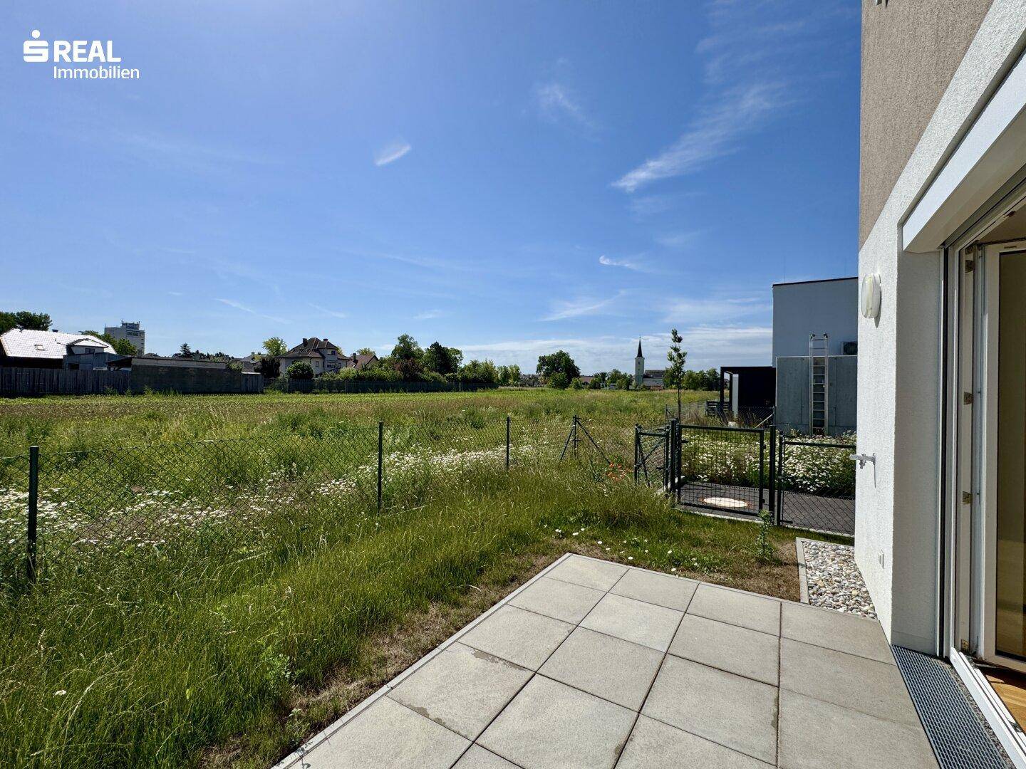 Terrasse mit weitem Blick über eine grüne Wiese und den ländlichen Horizont.