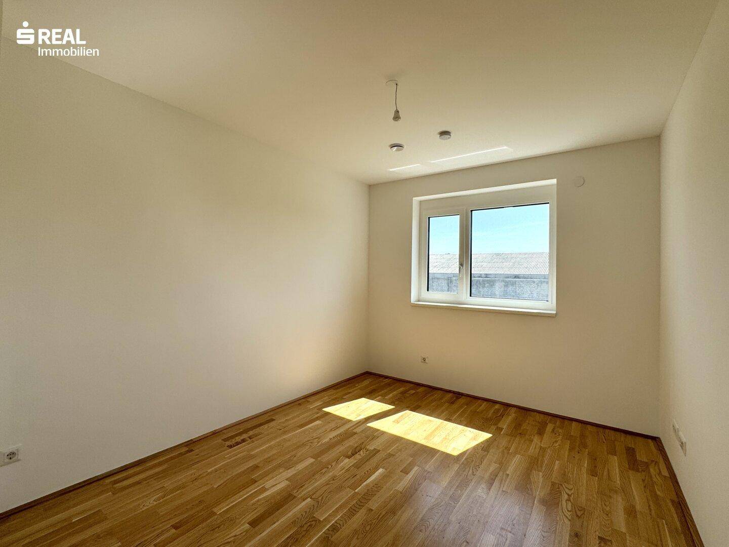 Freundliches Schlafzimmer mit Parkettboden und Fenster, das den Raum gut belichtet.