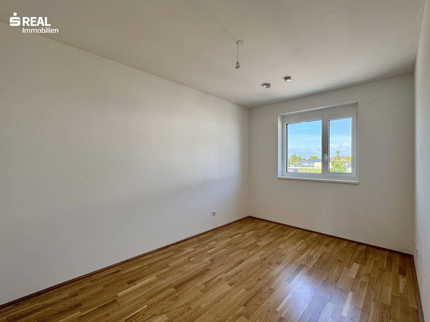 Geräumiges Schlafzimmer mit Holzboden und Fenster, bietet eine ruhige Atmosphäre.