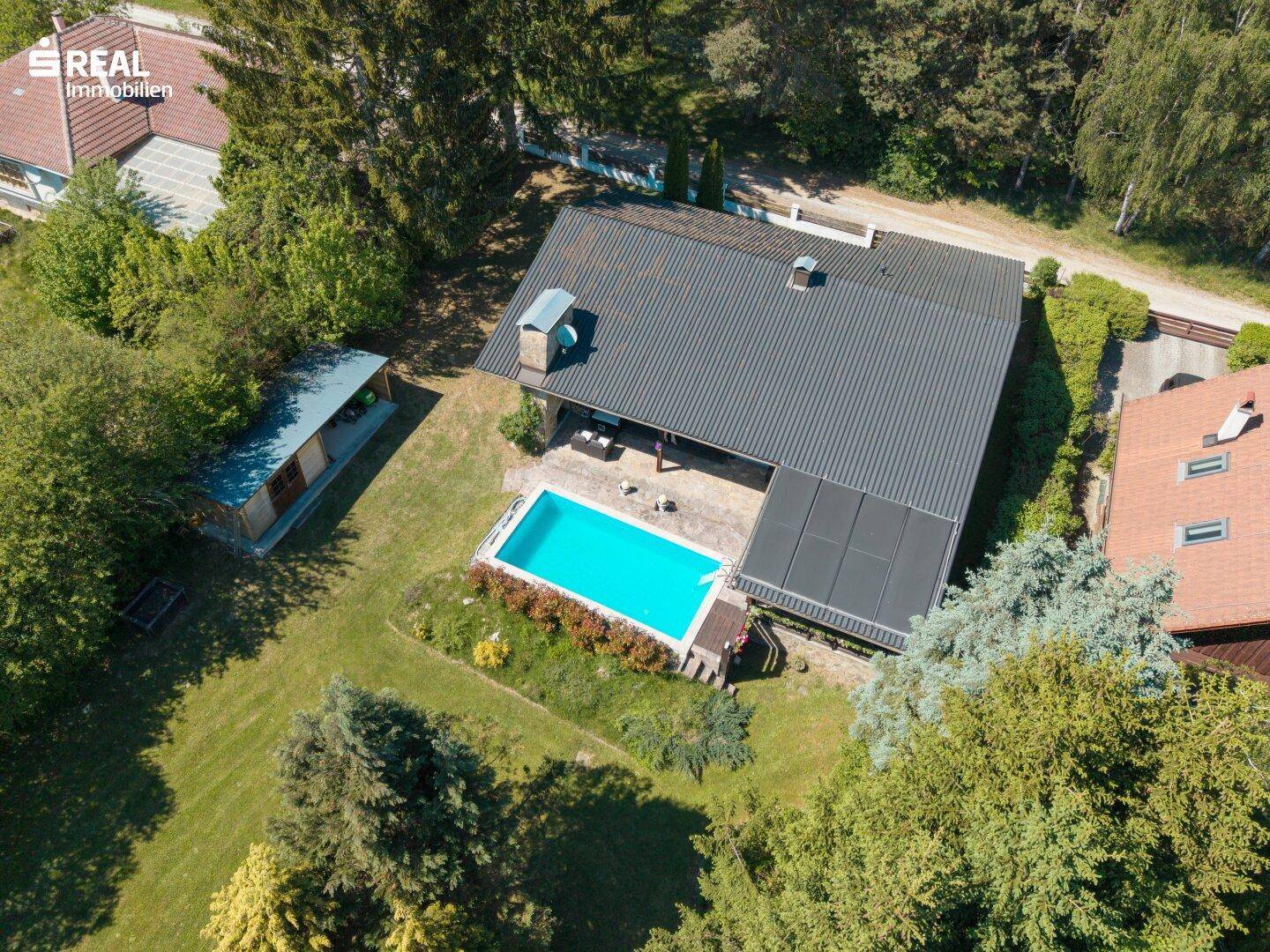 Luftaufnahme des Anwesens mit Haus, Pool, Garten und umgebenden Bäumen.