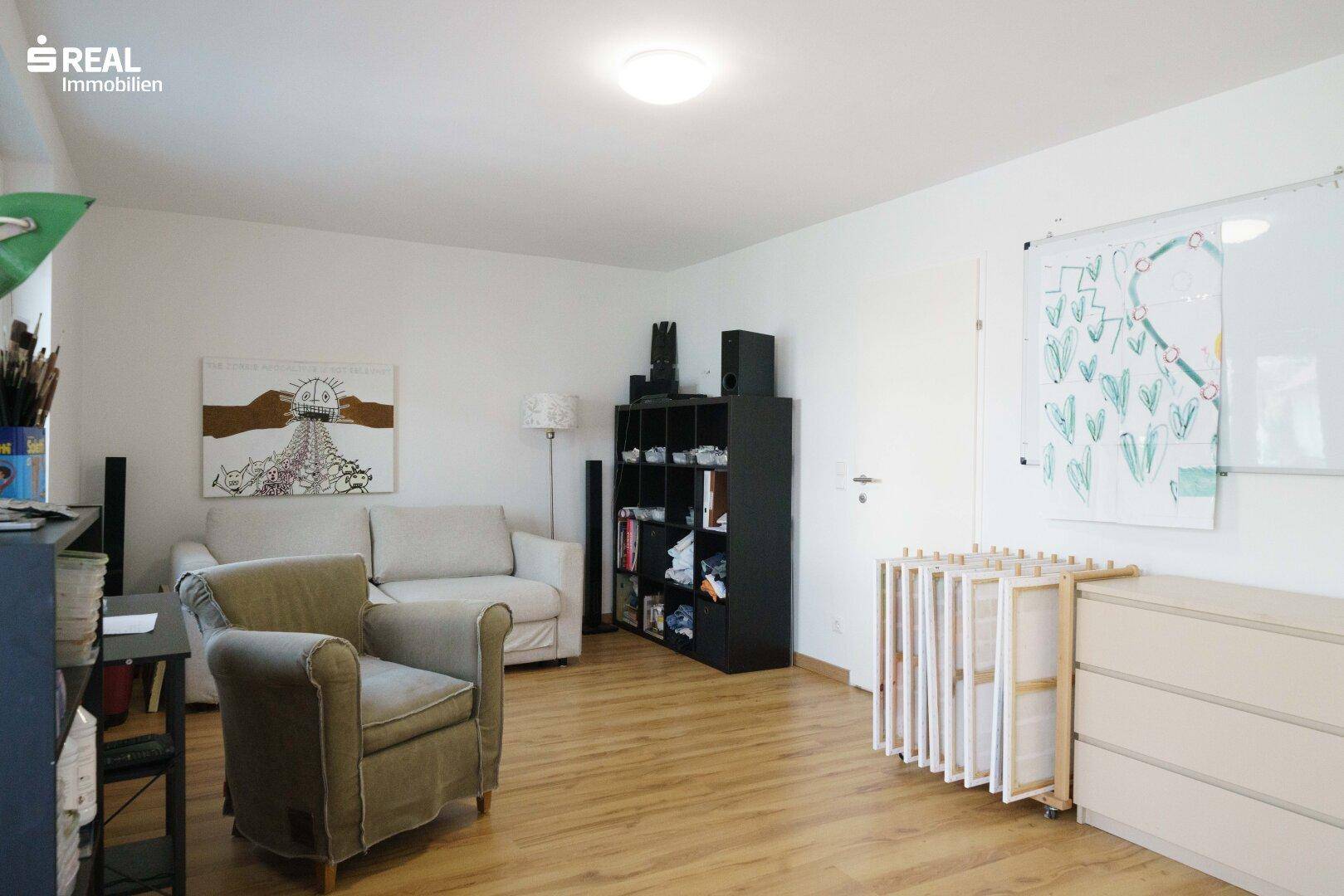 Heller Wohnbereich mit Holzboden, gemütlichem Sofa und einem Bücherregal, ideal für Entspannung.