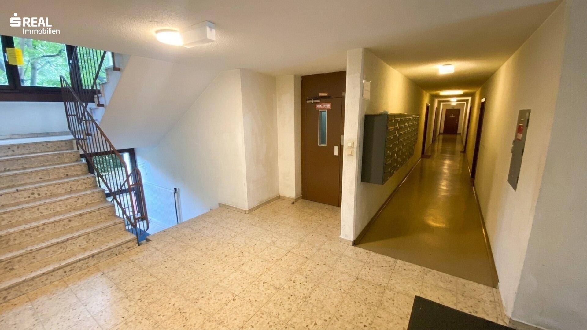 Gemeinschaftlicher Treppenhausbereich mit Aufzug, Fliesenboden und Zugang zu den Wohnungen.