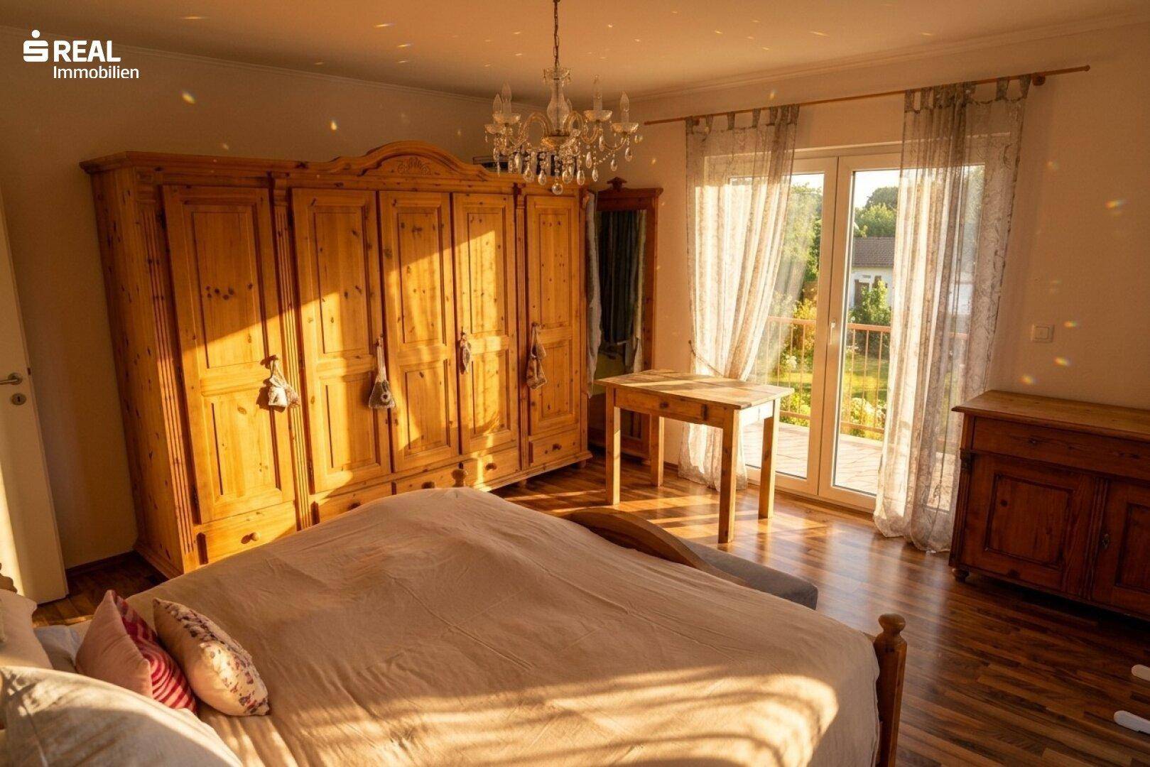 Schlafzimmer mit traditionellem Holzschrank, Holzboden und Zugang zum Balkon.