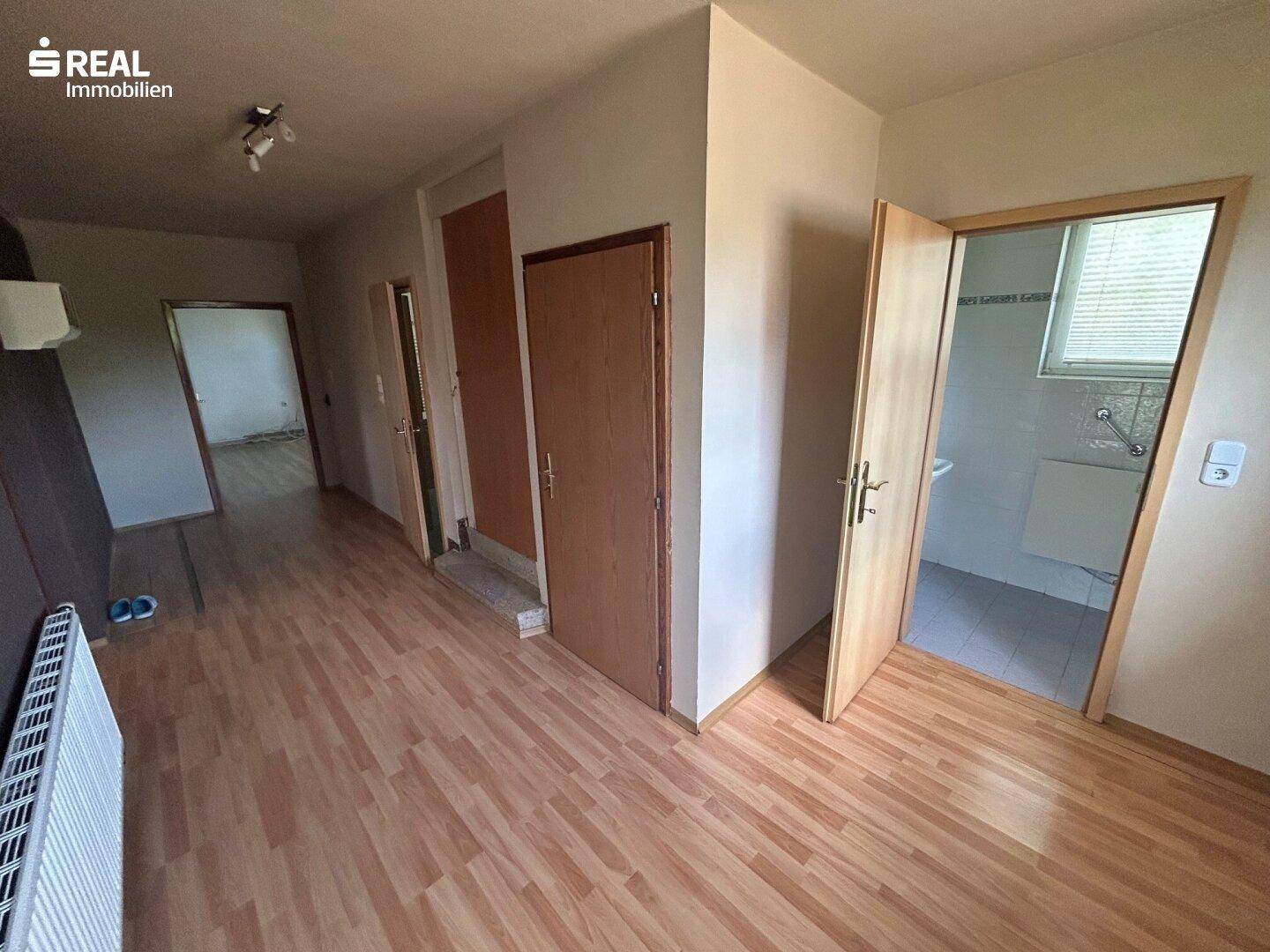 Flur mit Laminatboden und Zugang zu weiteren Zimmern und einem Badezimmer.