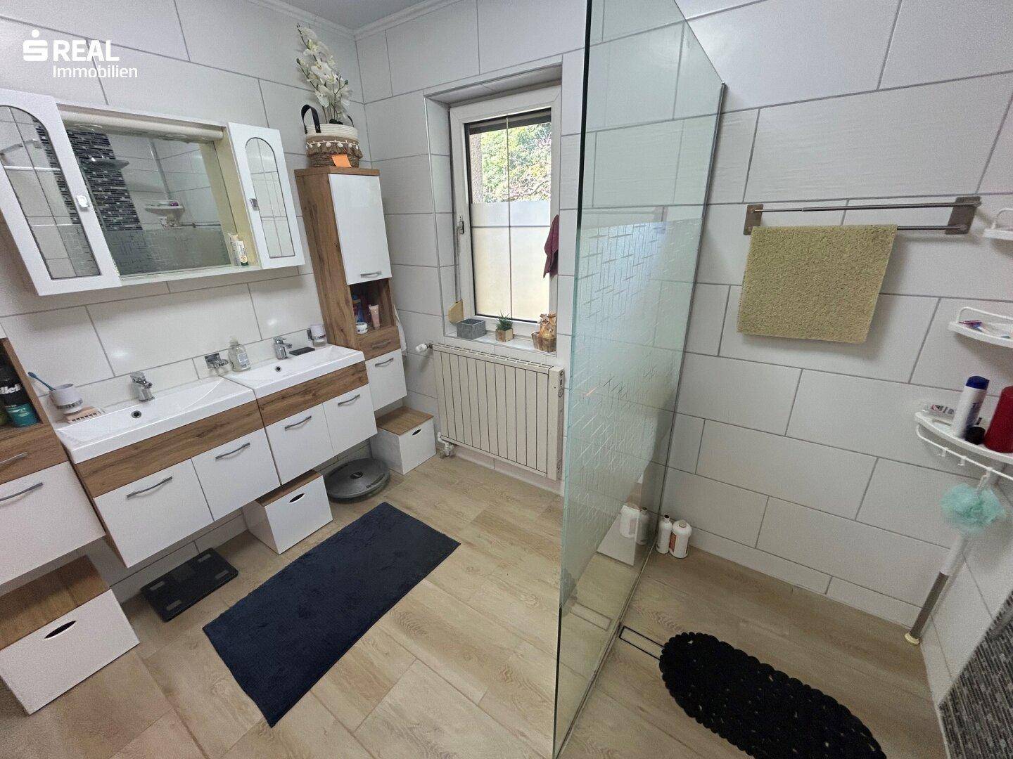 Modernes Badezimmer mit Doppelwaschbecken, großer begehbarer Dusche und Fenster.