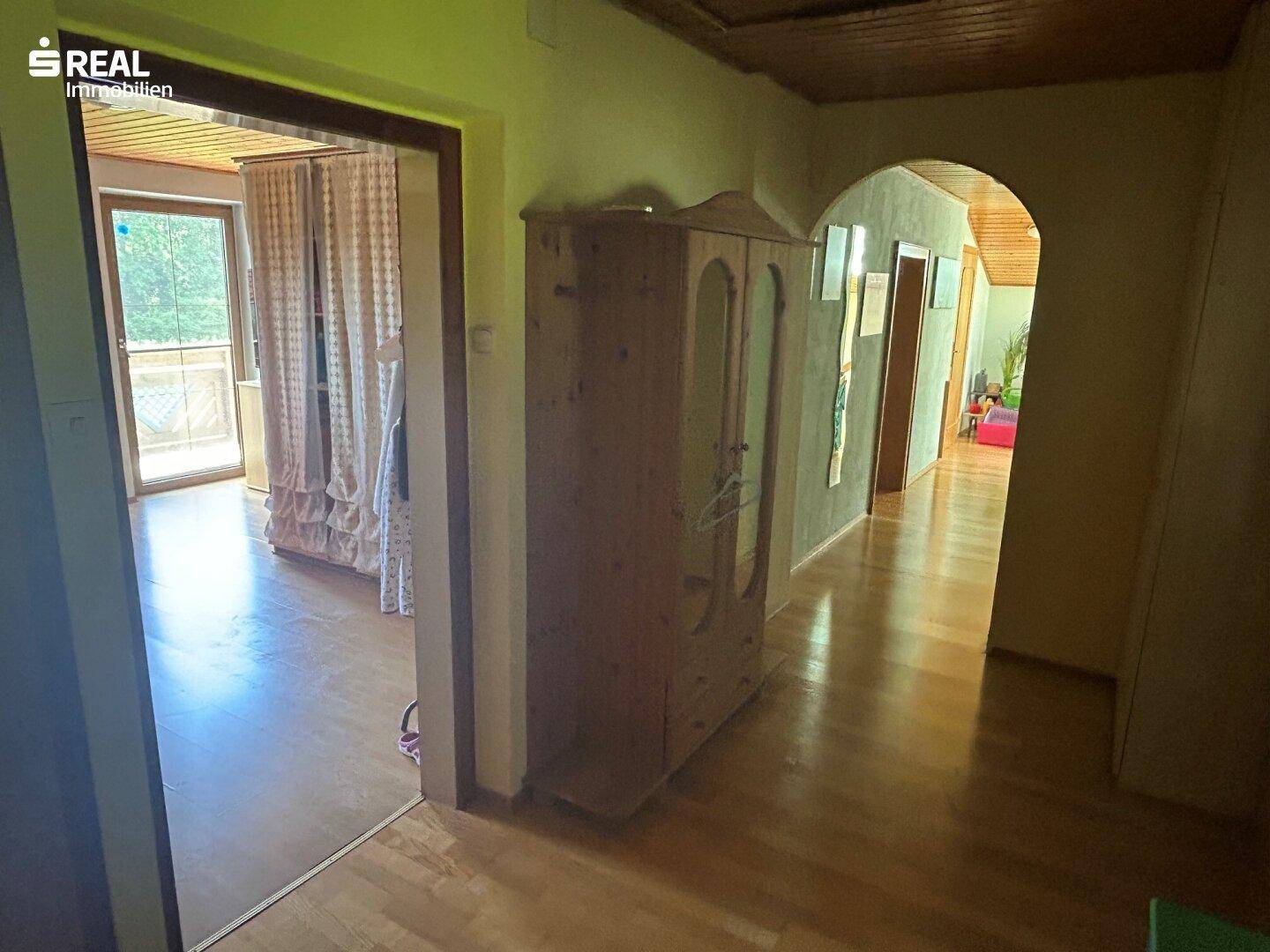 Langer Flur mit Laminatboden, Holzschrank und Zugang zu weiteren Zimmern.
