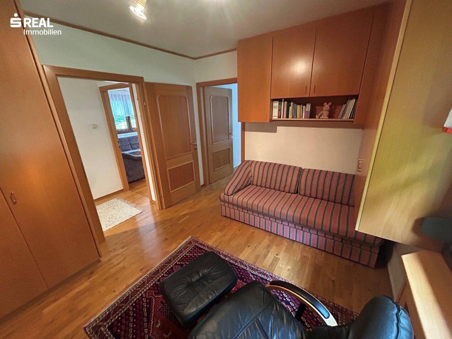 Vielseitiger Raum, ideal als Büro oder Gästezimmer, mit Schlafsofa und Holzmöbeln.