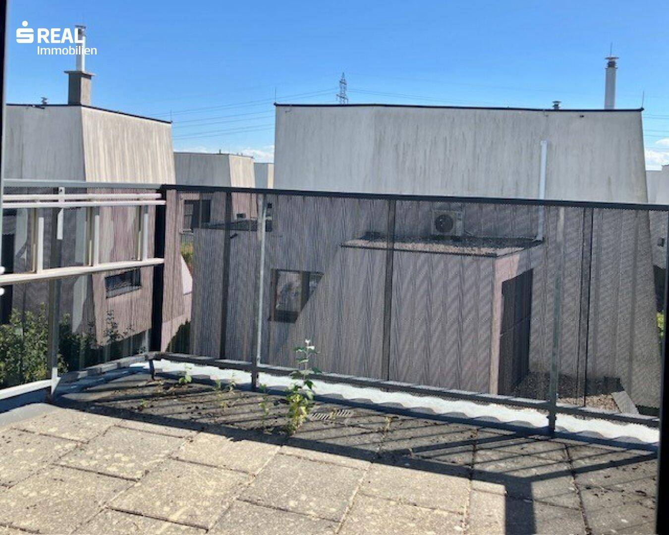 Dachterrasse mit Blick auf die umliegenden Gebäude und den Himmel.