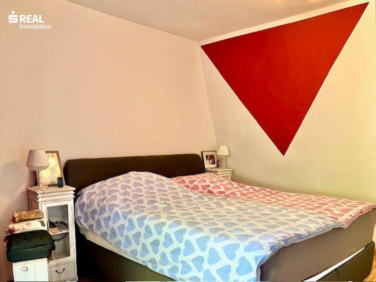 Schlafzimmer mit Doppelbett und einer auffälligen roten Akzentwand.