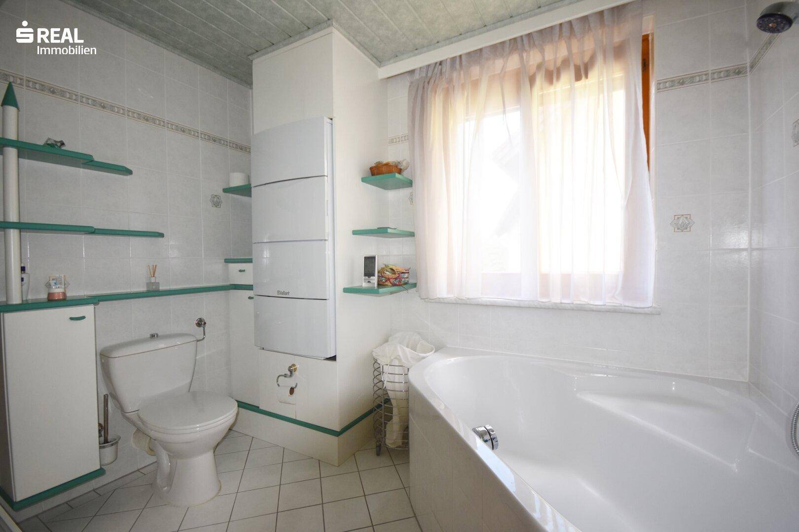 Badezimmer mit Badewanne, WC und Fenster für natürliche Belüftung.
