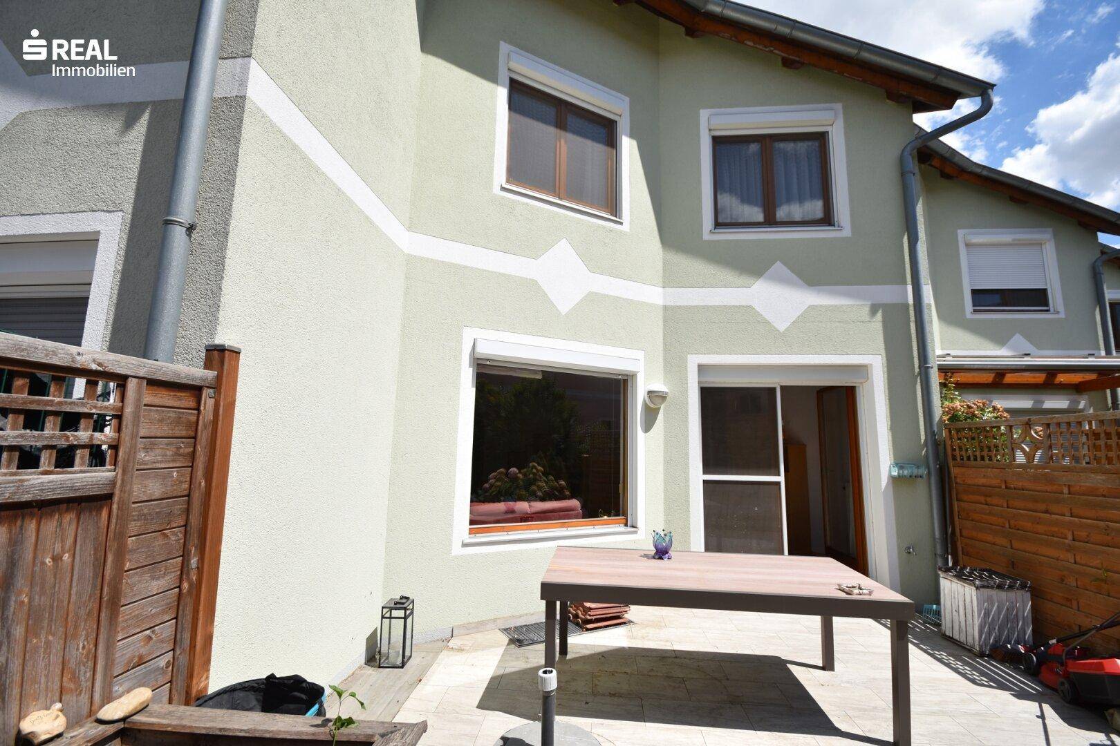 Terrasse am Haus mit Esstisch und Zugang zum Garten.