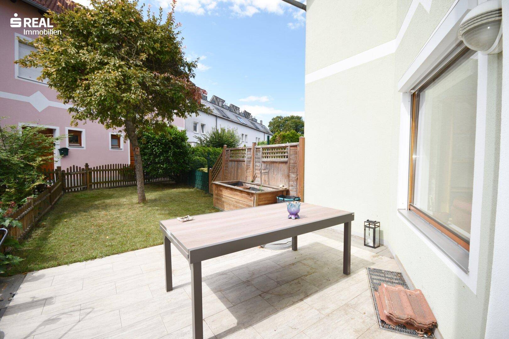Gemütliche Terrasse mit Esstisch und Zugang zum privaten Gartenbereich.
