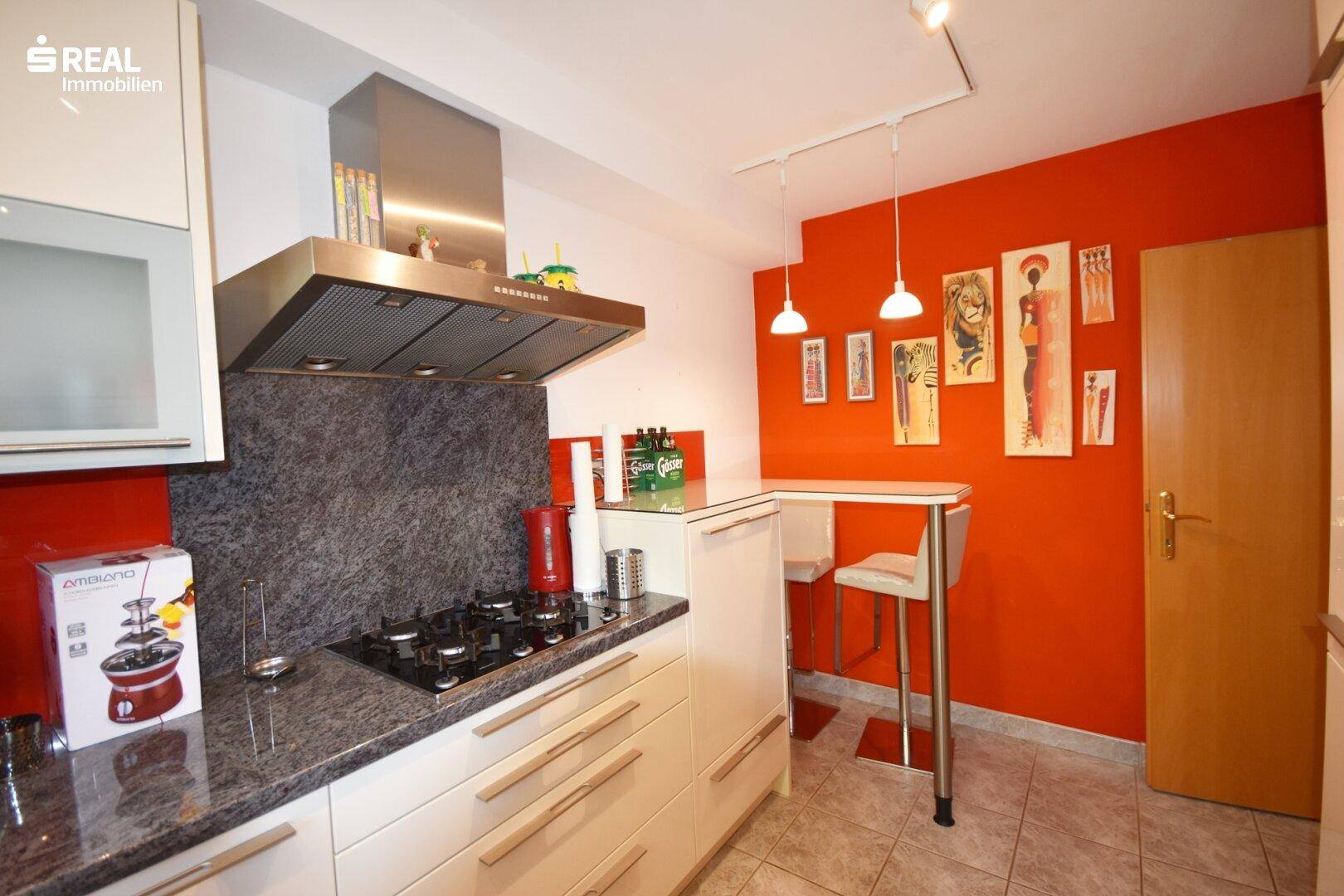 Moderne Küche mit weißen Fronten, Granitarbeitsplatte und farbiger Akzentwand.