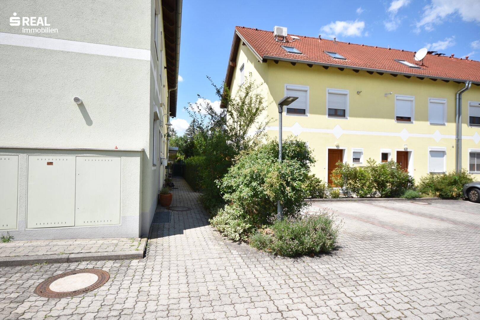 Außenansicht der Wohnanlage mit Parkplätzen und gepflegter Grünfläche.