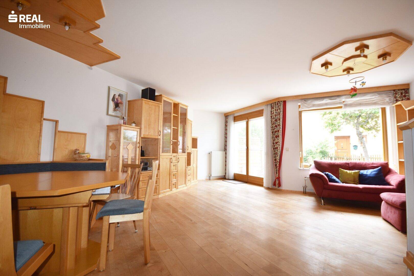 Heller Wohnbereich mit Holzboden, bequemer Couch und Blick in den Garten.