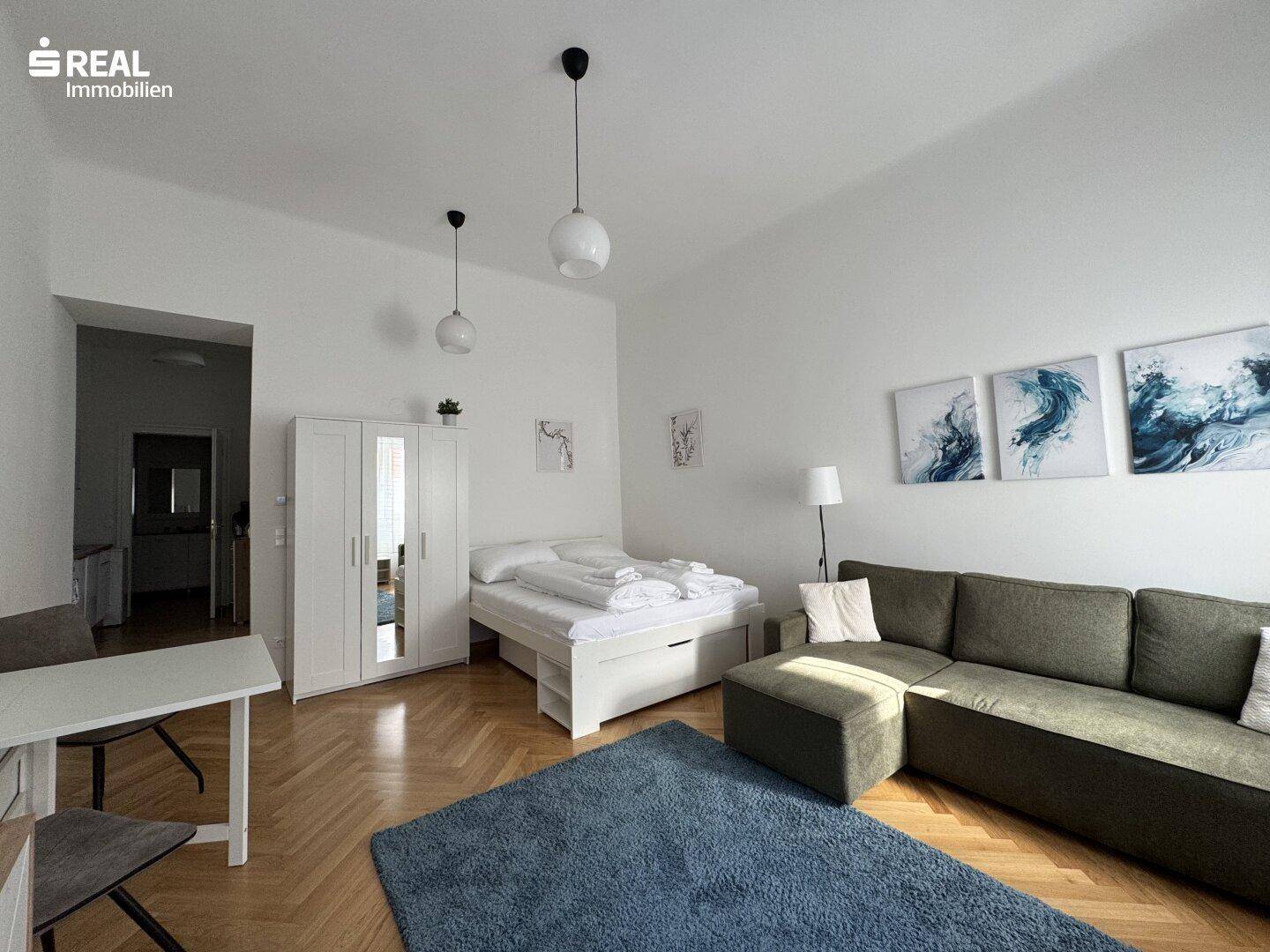 Gemütlicher Wohnbereich mit Schlafgelegenheit, Sofa und Kleiderschrank, ausgestattet mit Holzparkett.