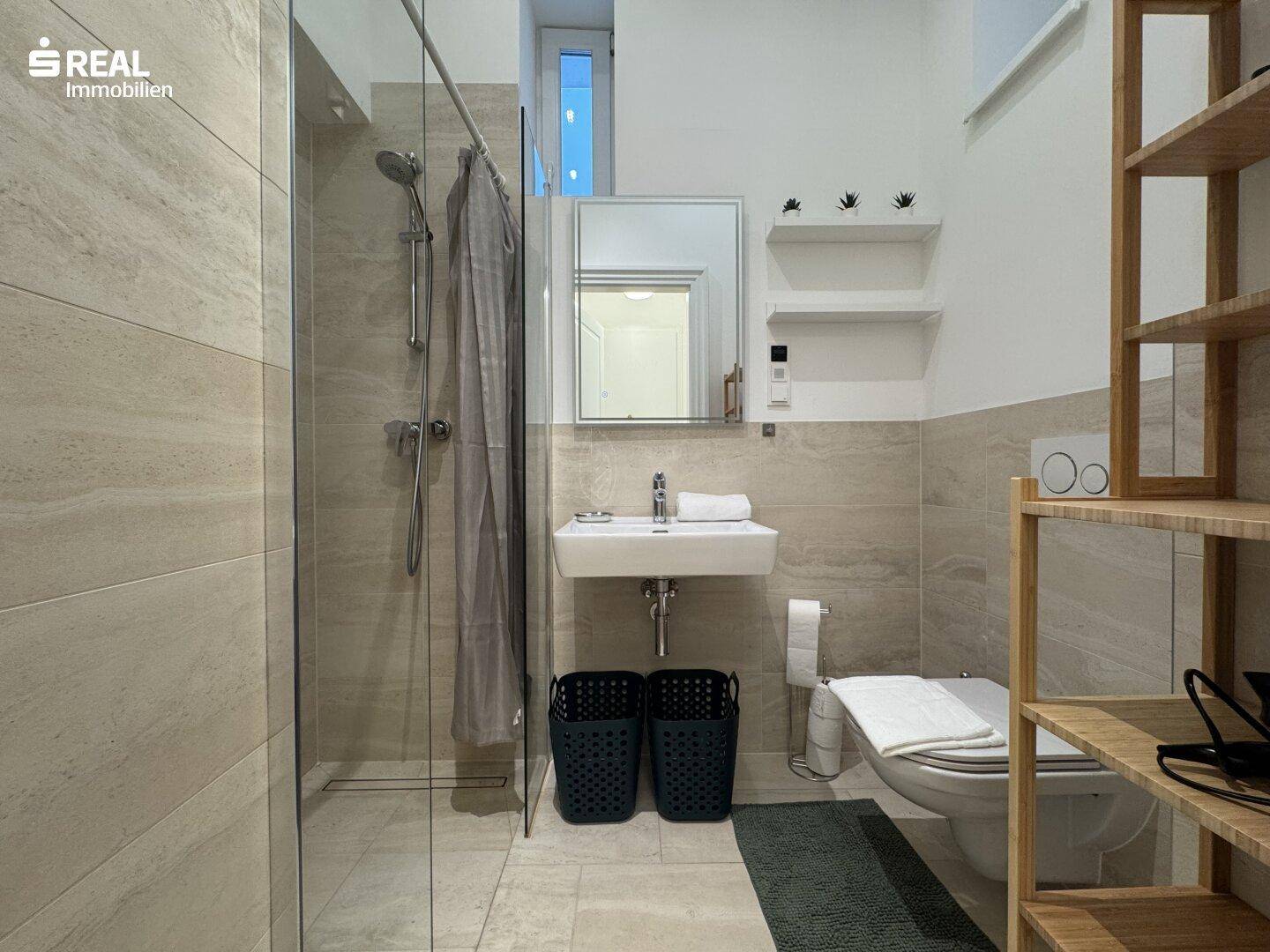 Modernes Badezimmer mit begehbarer Dusche, Wand-WC und hellen Fliesen.