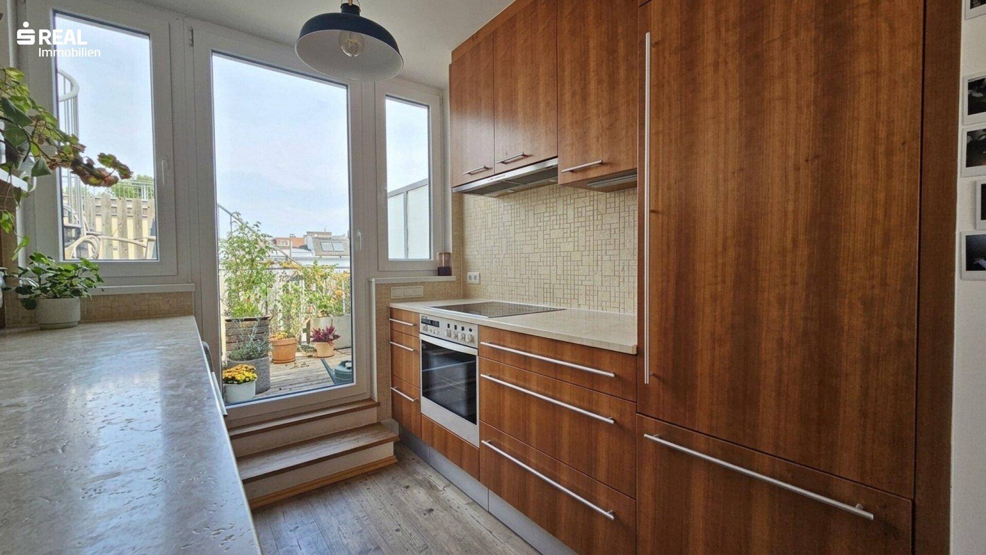 Helle Holzküche mit integrierten Geräten, Arbeitsplatten und direktem Zugang zur Terrasse.