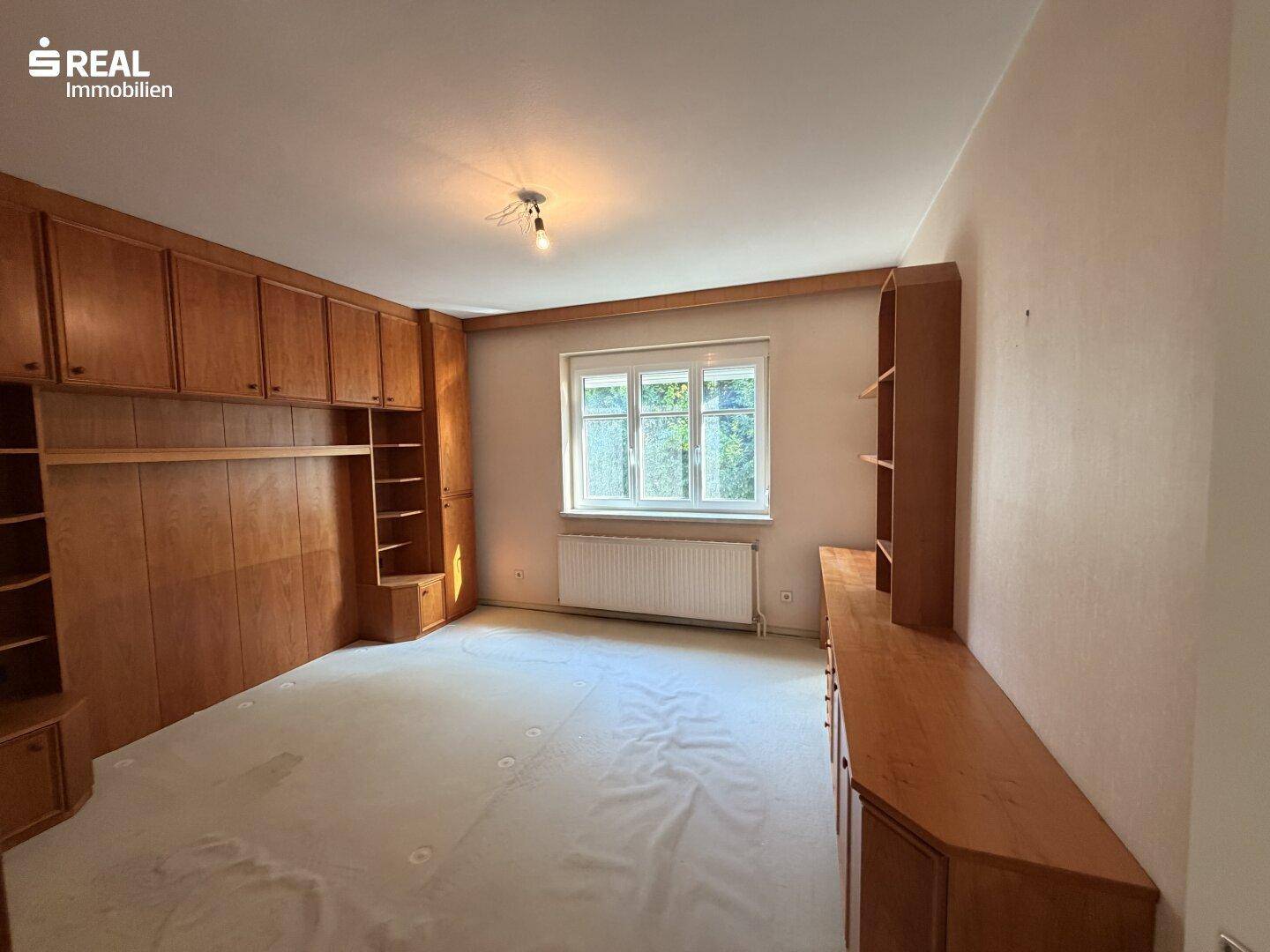 Helles Schlafzimmer mit Einbauschränken aus Holz und Teppichboden, gut gepflegt.