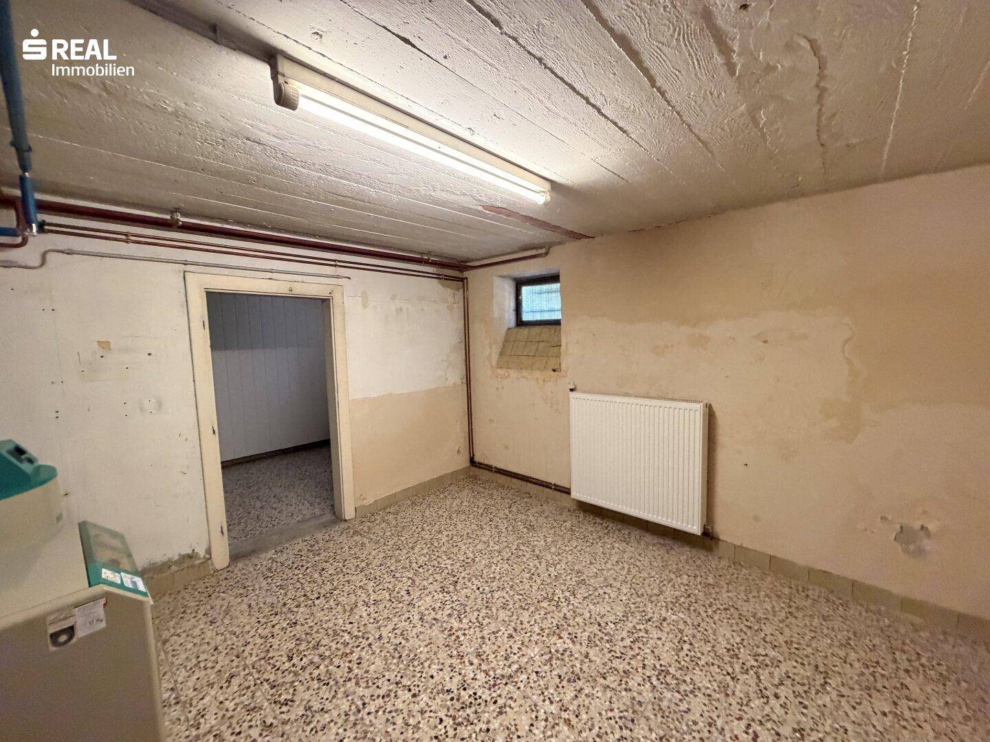 Kellerraum mit Beton-Decke, kleinem Fenster und Heizkörper, ideal als Abstellraum.