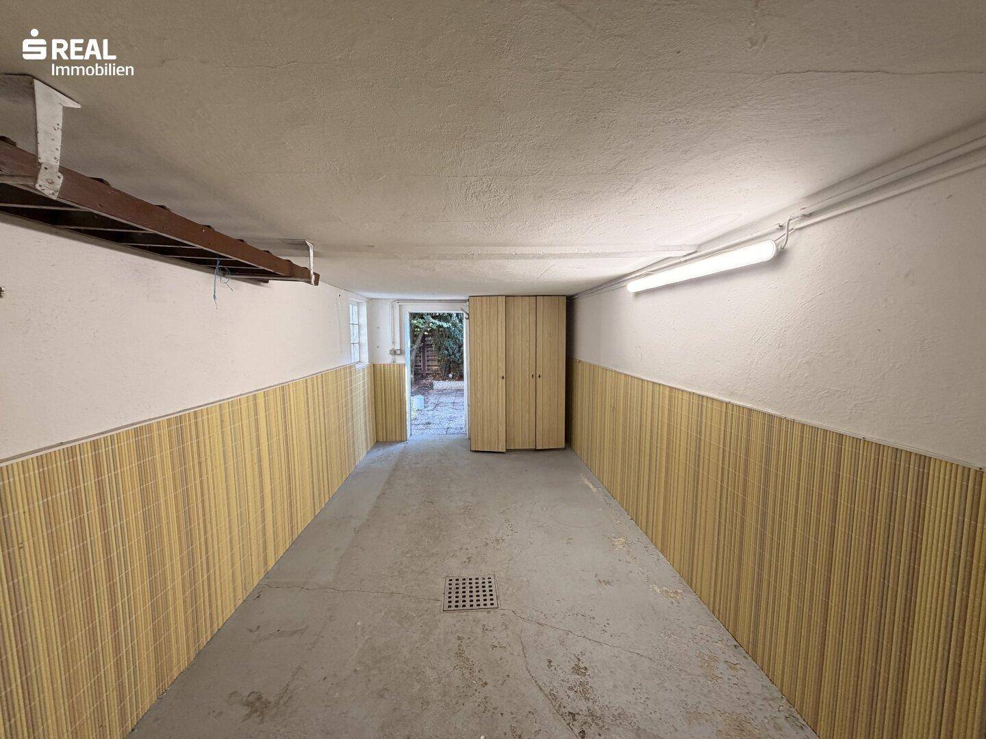 Garage mit Zugang zum Außenbereich und Betonboden, ideal für Fahrzeuge und Lagerung.