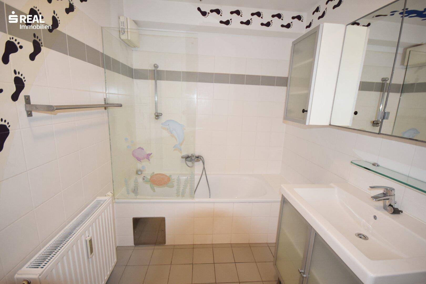 Badezimmer mit Badewanne, Waschbecken und verspielten Wanddekorationen.
