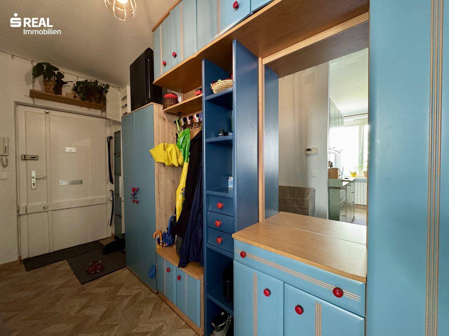 Eingangsbereich mit farbenfroher Garderobe, Spiegel und Zugang zu den Wohnräumen.
