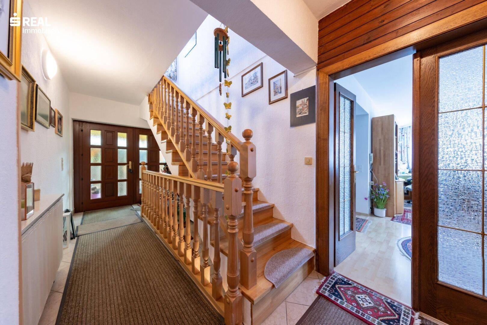 Heller Flur mit Holztreppe und traditionellen Holztüren.