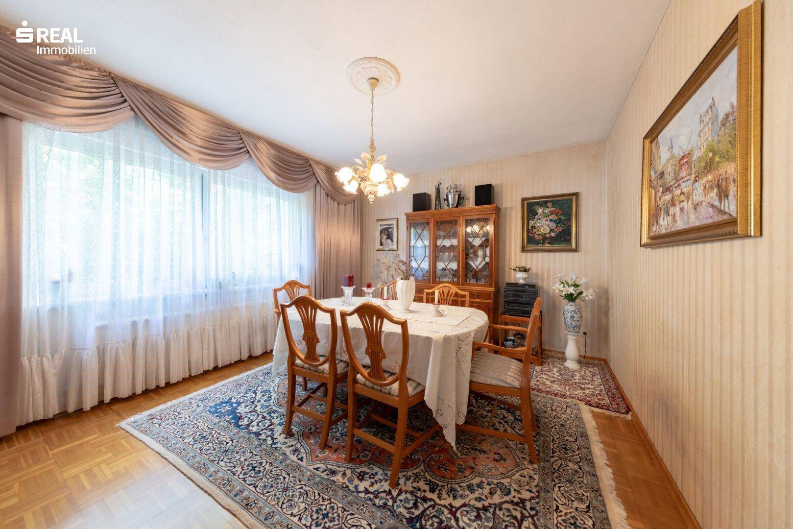 Eleganter Essbereich mit großem Holztisch, passenden Stühlen und gemusterter Tapete.