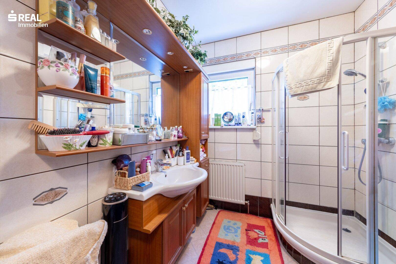 Badezimmer mit Duschkabine, Einzelwaschbecken und hellen Fliesen.