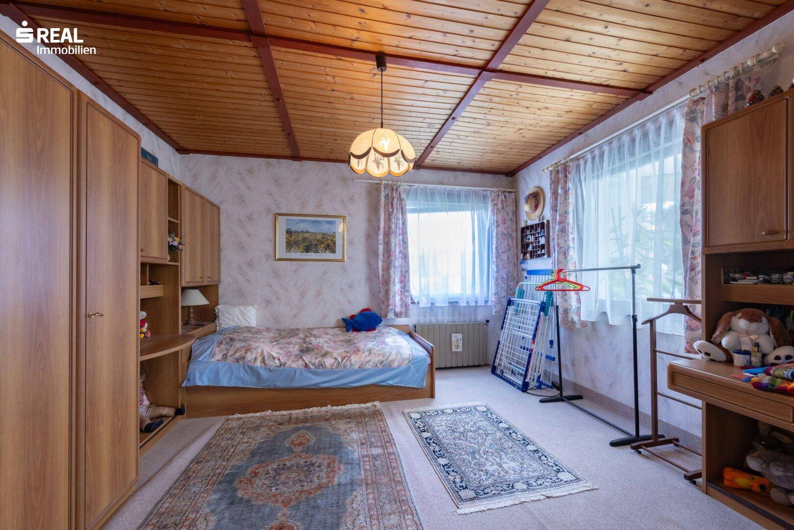 Schlafzimmer mit Holzdecke, Einzelbett und traditioneller Einrichtung.