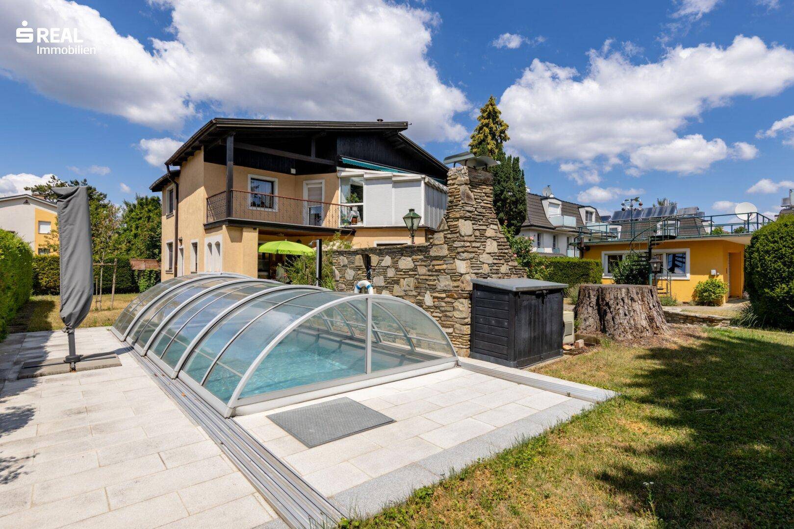 Ansicht des Hauses vom Garten aus mit überdachtem Pool und gemauertem Grillbereich.