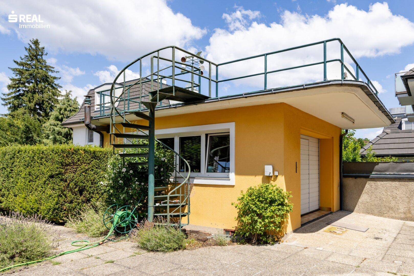 Nebengebäude mit Außentreppe, die zu einer Dachterrasse führt.