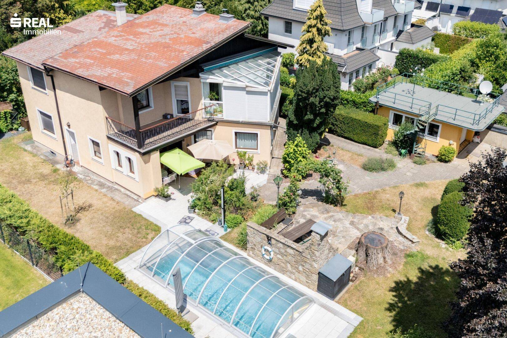 Übersicht des Anwesens mit Haupthaus, Garten, Pool und umliegender Bebauung.