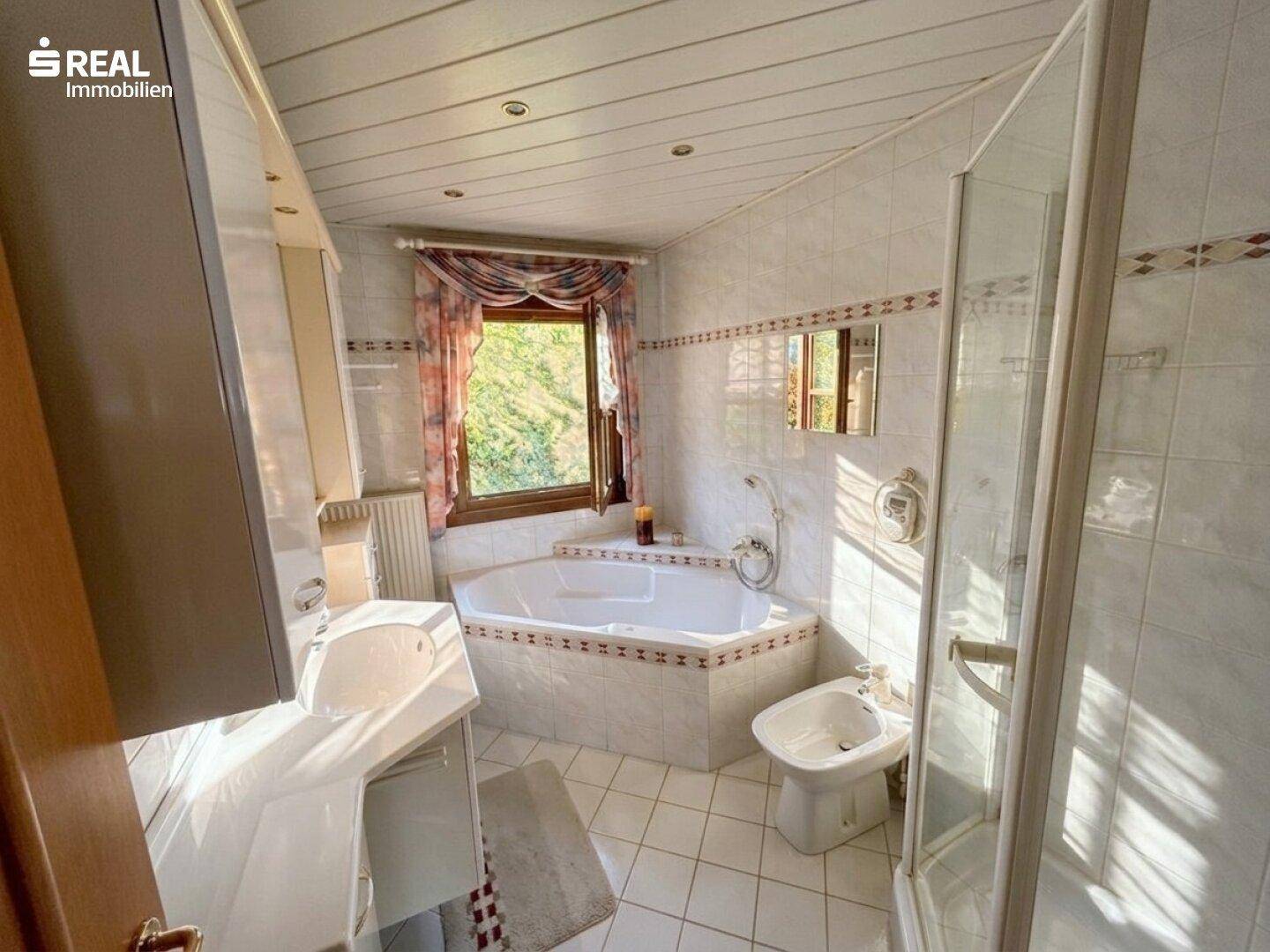 Badezimmer mit Eckbadewanne, separater Dusche, Bidet und Fenster für Tageslicht.
