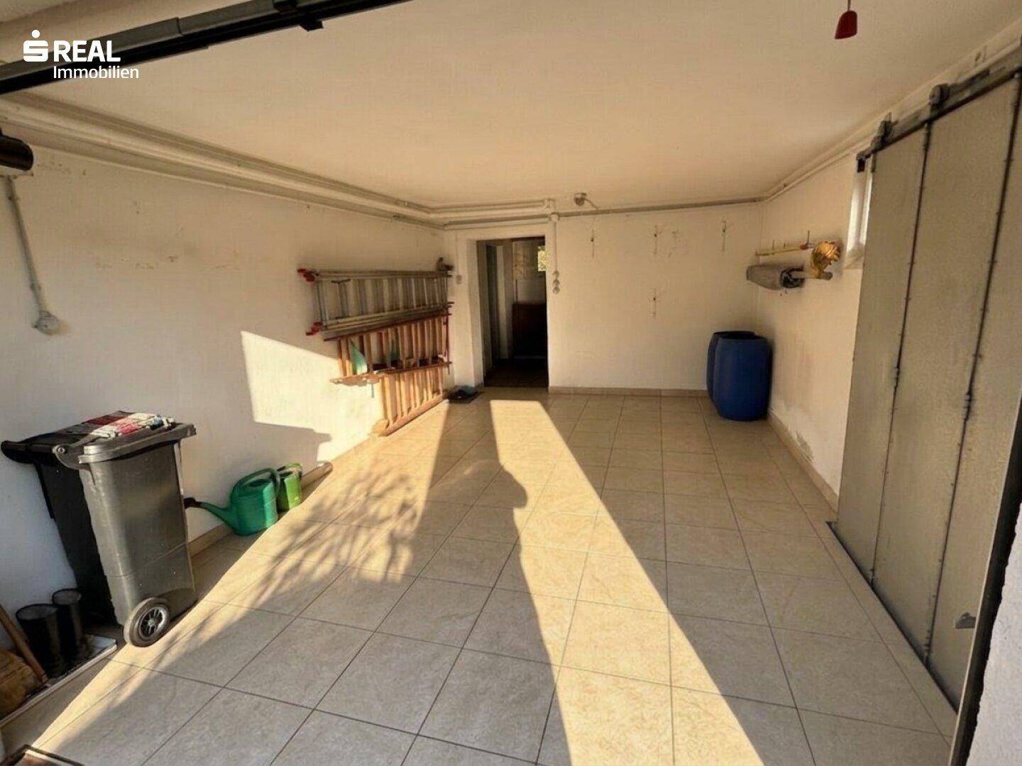 Geräumige Garage mit Fliesenboden und ausreichend Platz für Fahrzeuge und Lagerung.