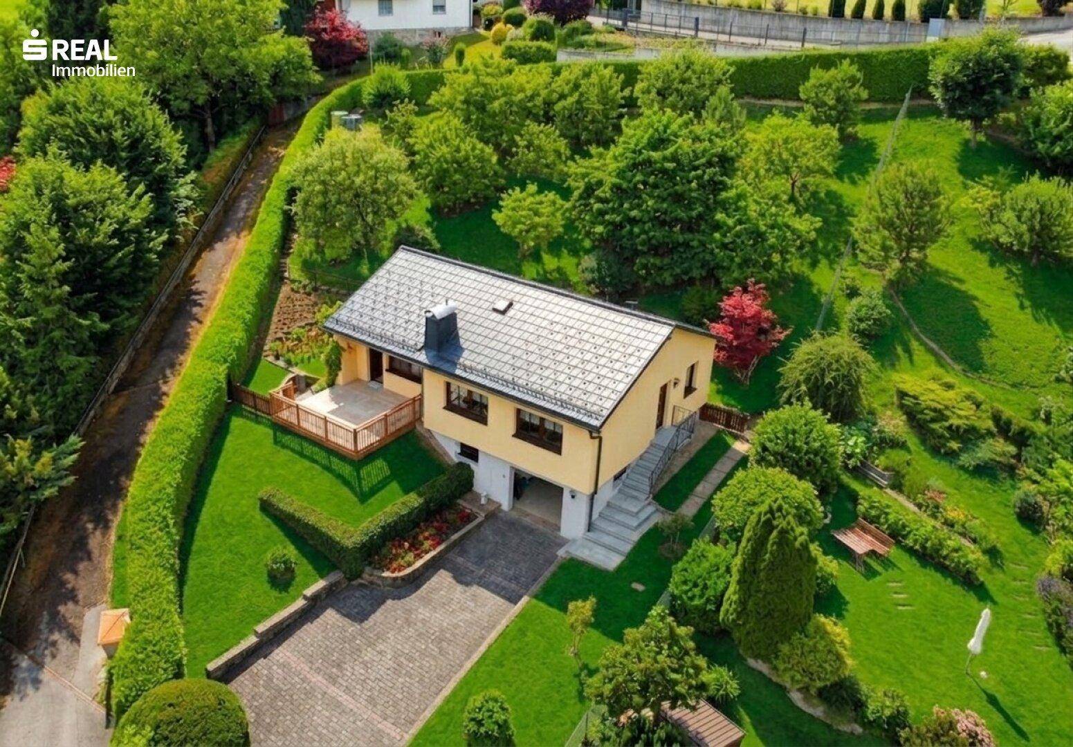 Vogelperspektive des Hauses mit weitläufigem Garten und sonniger Terrasse in grüner Umgebung.
