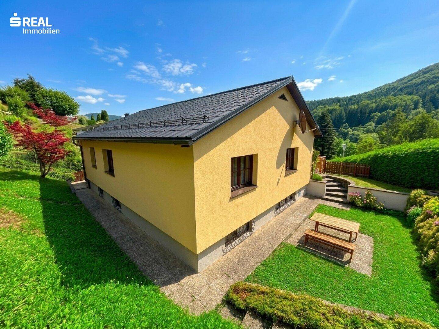 Seitenansicht des Hauses mit Rasenfläche, Picknicktisch und weitem Blick in die Natur.